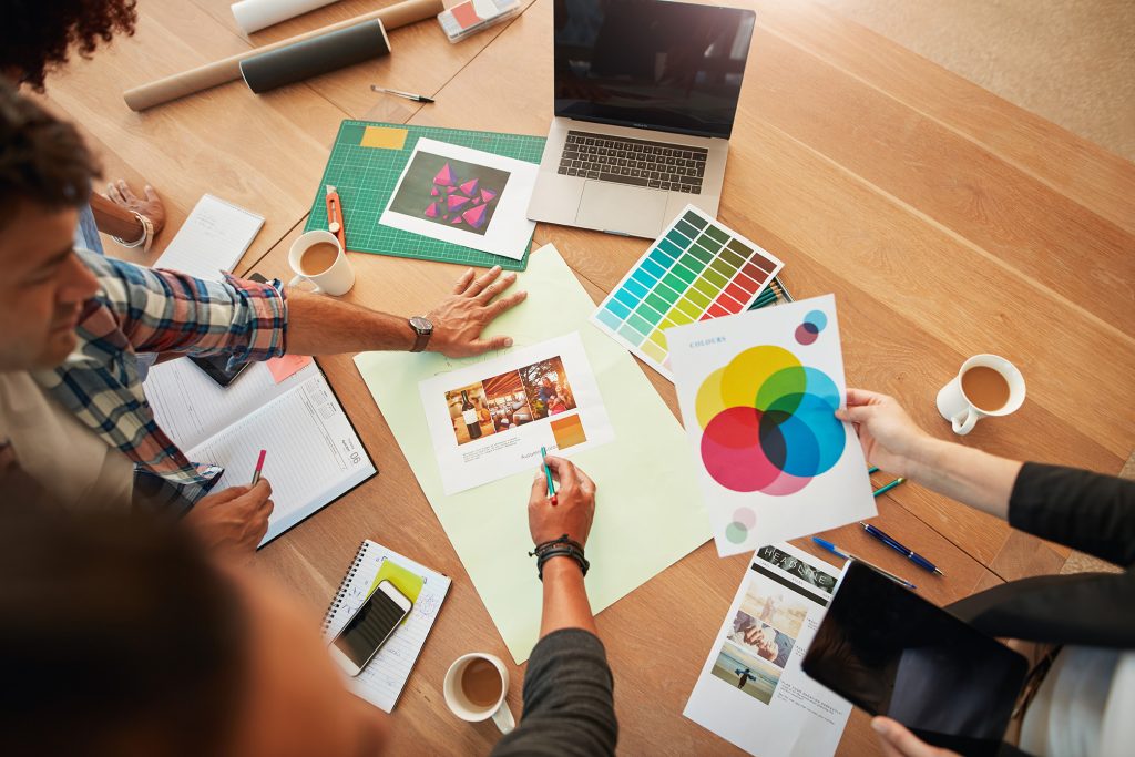 Top view shot of group of creative designers discuss the color palette during meeting. Creative team brainstorming around table.